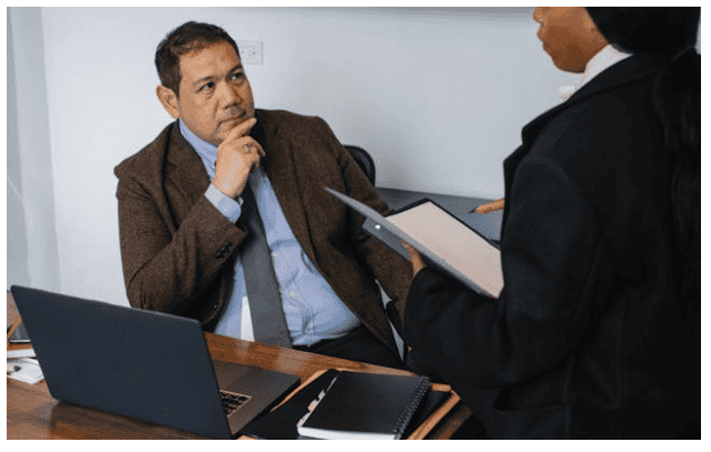 A man in a suit and tie engages in conversation with a woman dressed in a business suit.